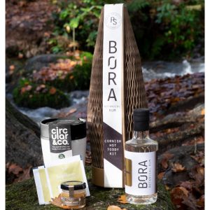 Hot toddy giftset sitting on rocks showing bottle of rum, cup, honey and teabag